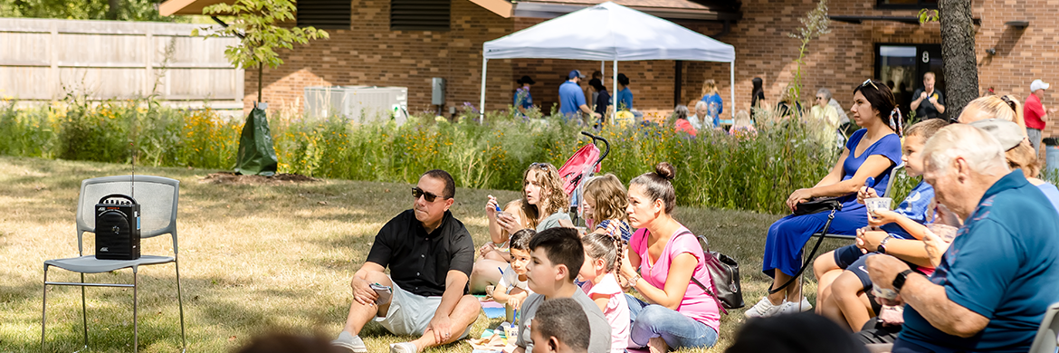Group of attendees sitting in the library backyard during a community event