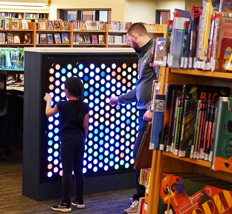 Father and child playing with the Everbright Wall inside the library
