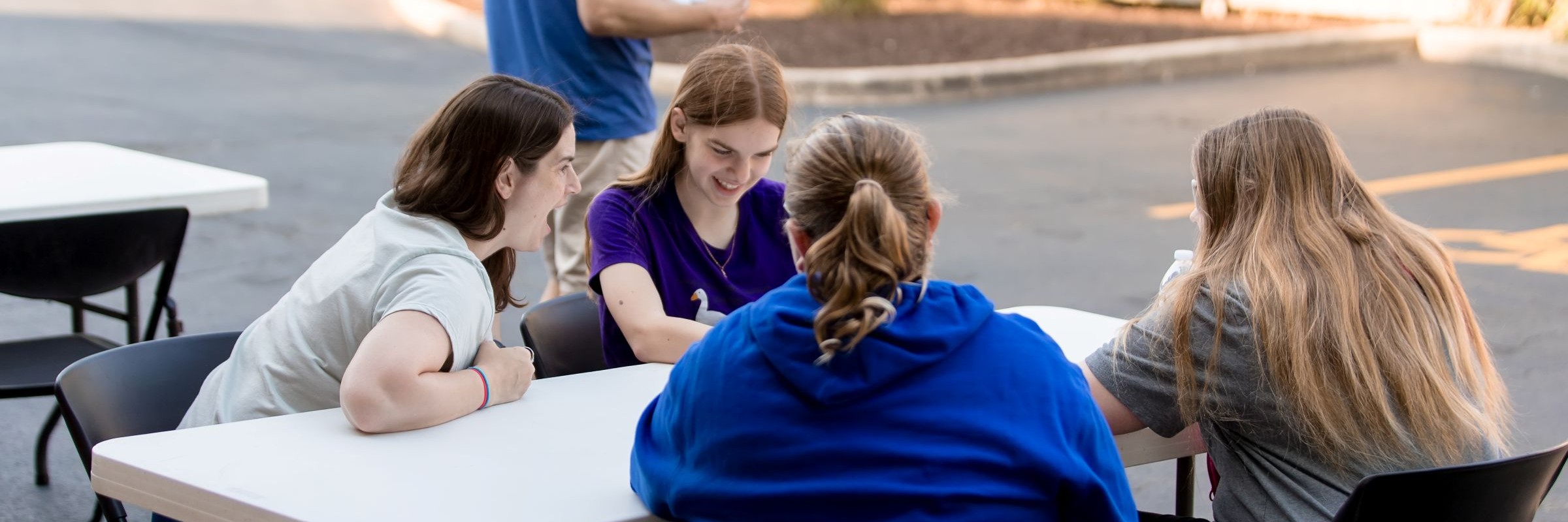 Four teen girls gather around a table outside the library