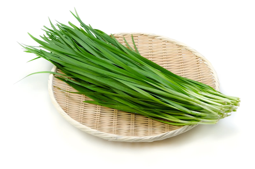 A clump of garlic chives resting on a woven mat.