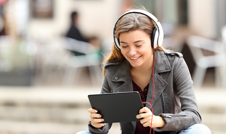 Smiling teen girl with tablet in hand and headphones on