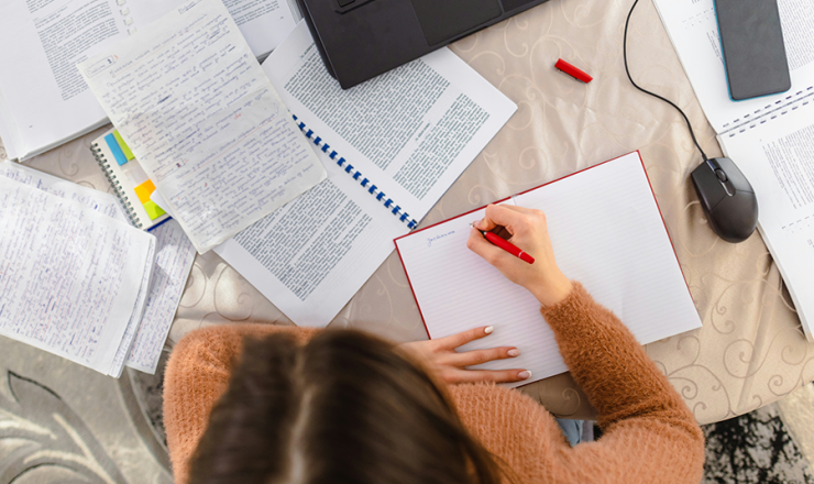 Teen girl with papers and homework spread out with an open laptop